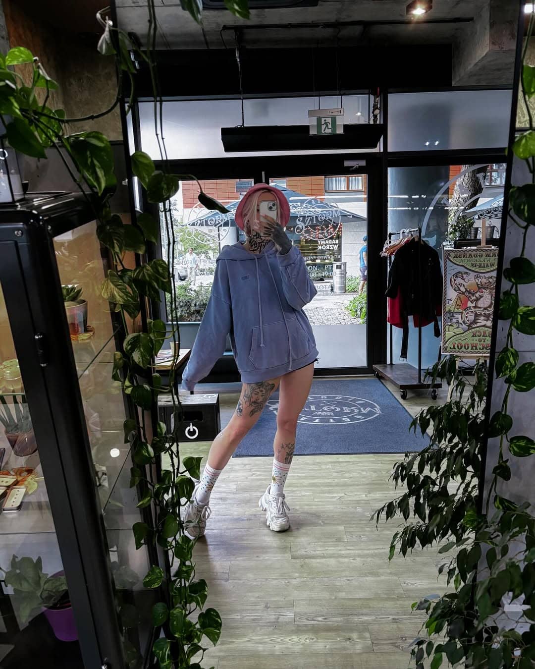 Kobiece zdjęcie ntatuatorki otoczonej roslinami z nutą tajemniczości wykonane we wnetrzach studia tatuażu sztorm we Wrzeszczu