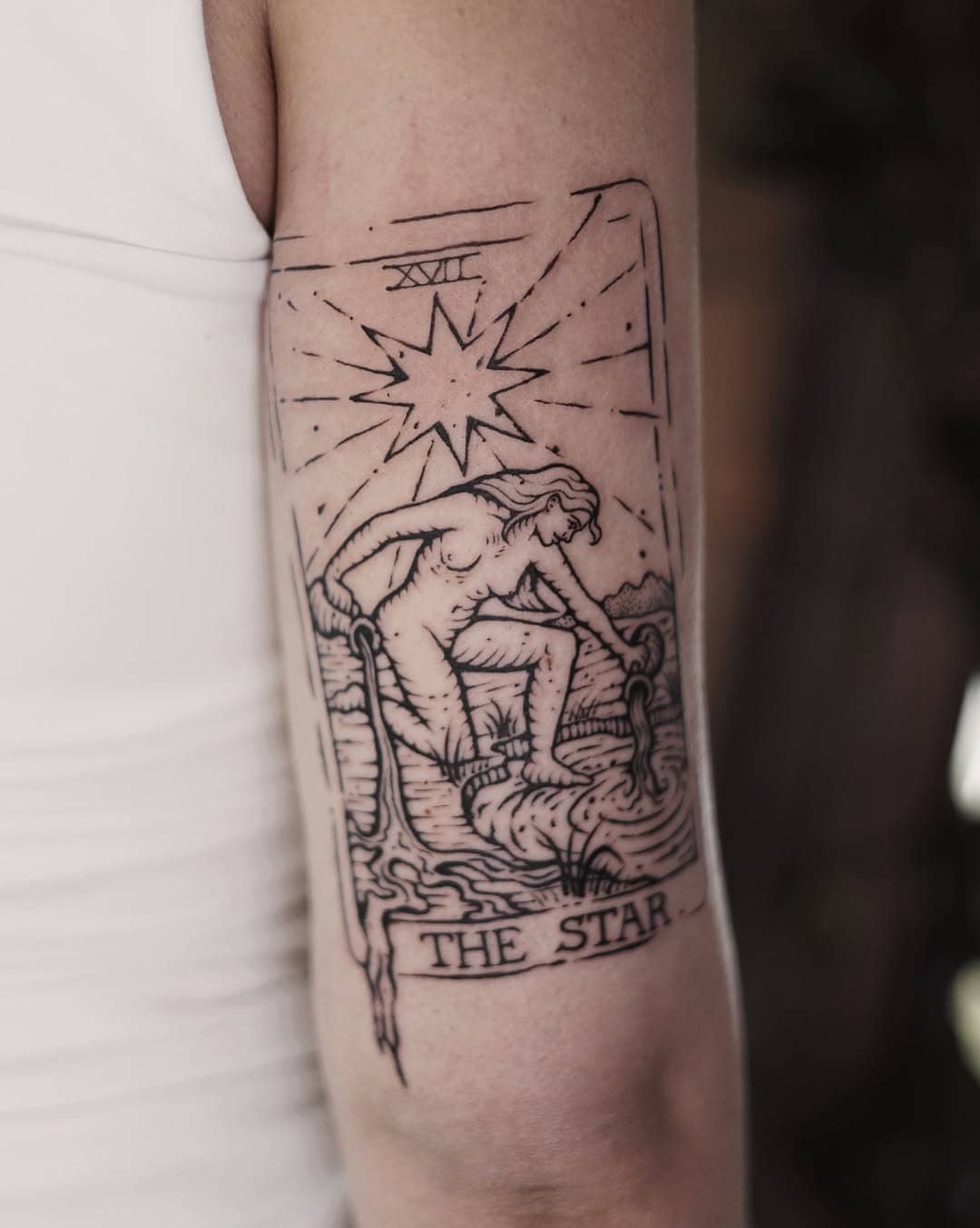 Tatuaż karty tarota „The Star” w stylu ryciny na ramieniu.