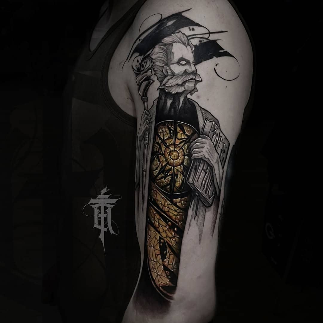 Tatuaż na ramieniu z postacią i złotymi akcentami, w stylu Art Craft Emila Cwika