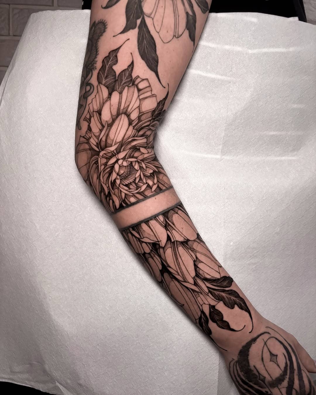 Delikatny tatuaż roślinny w stylu fineline tworzący rękaw na ramieniu – Nava, Sztorm Tattoo Gdańsk