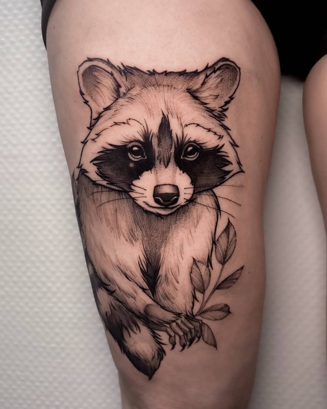 Tatuaż fineline przedstawiający realistycznego szopa z gałązką – Nava, studio Sztorm Tattoo Gdańsk