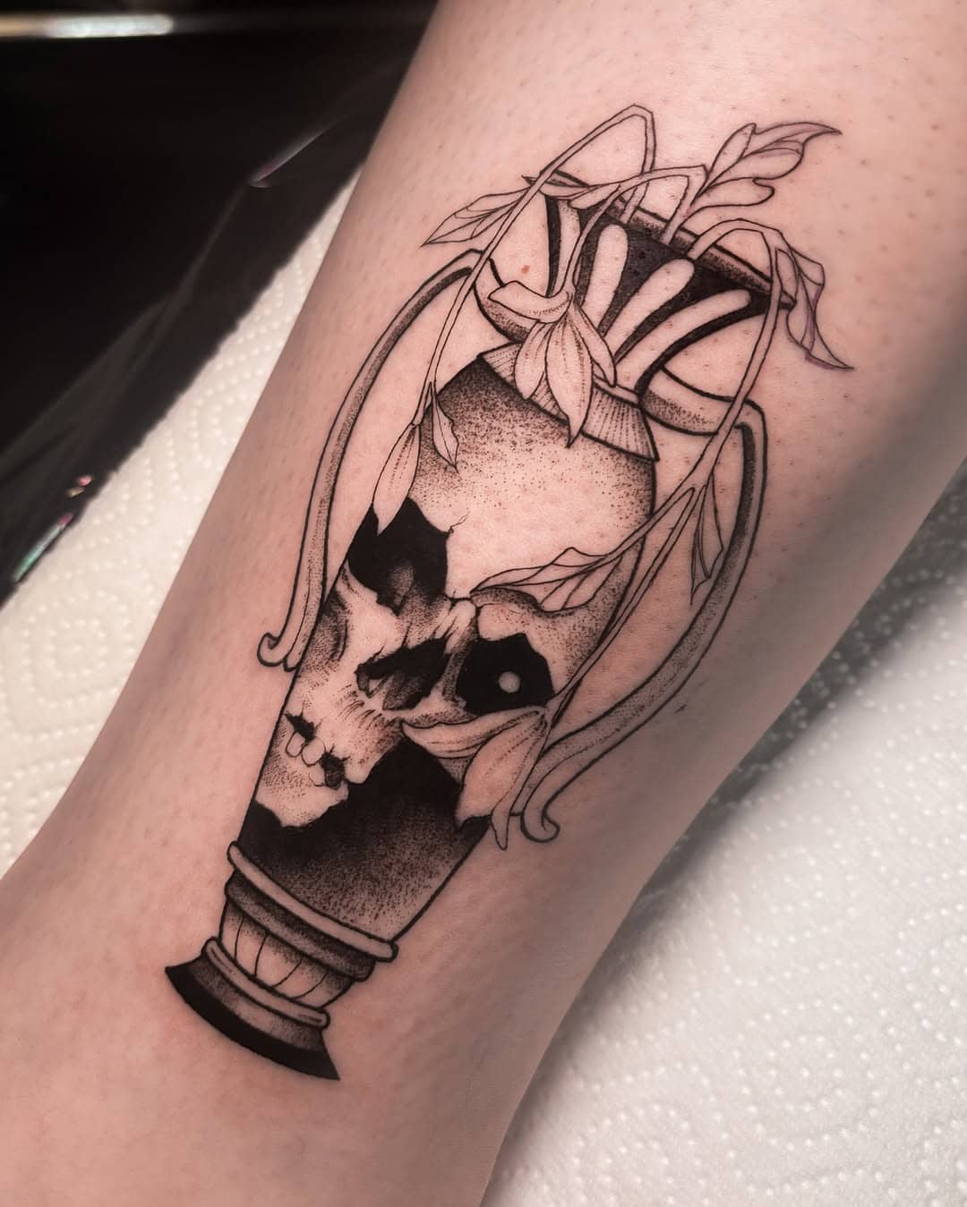Tatuaż w stylu fineline – czaszka w wazie oplecionej roślinami, Nava w Sztorm Tattoo Gdańsk