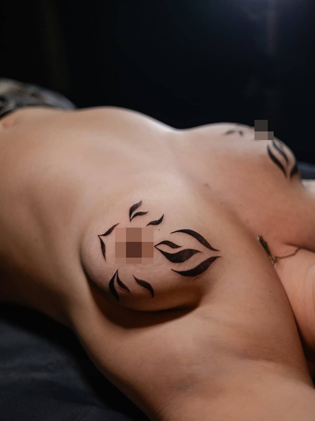 Tatuaż na piersiach w stylu graficznym, czarne płomienie otaczające sutki. Studio Sztorm Tattoo Gdańsk.