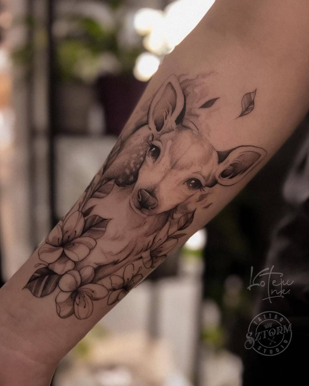 Tatuaż jelenia otoczonego kwiatami na przedramieniu – wykonanie Ola, Sztorm Tattoo Studio.