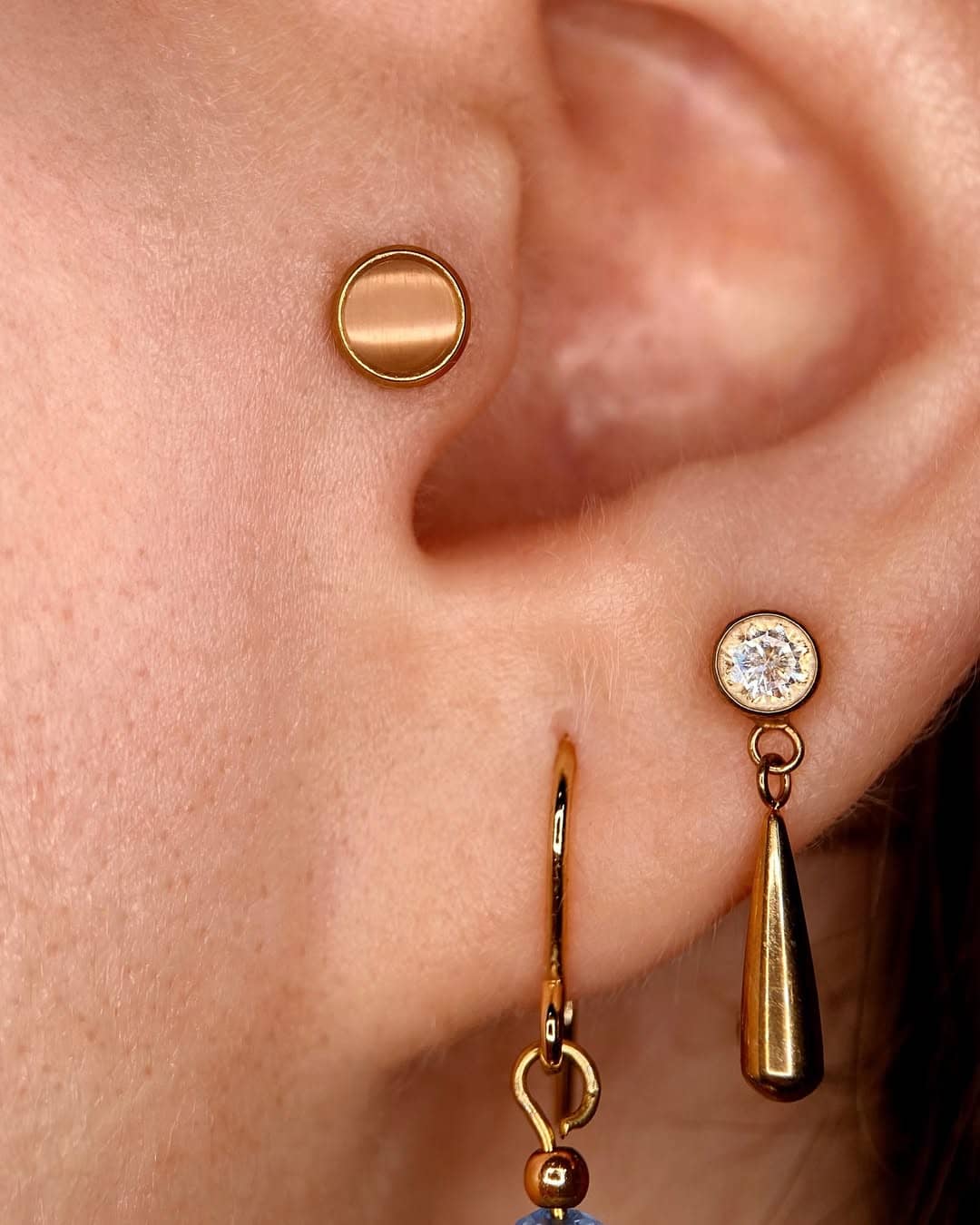 Złote kolczyki w płatku ucha wykonane metoda piercing czyli profesjonalne przekłucie igłą.