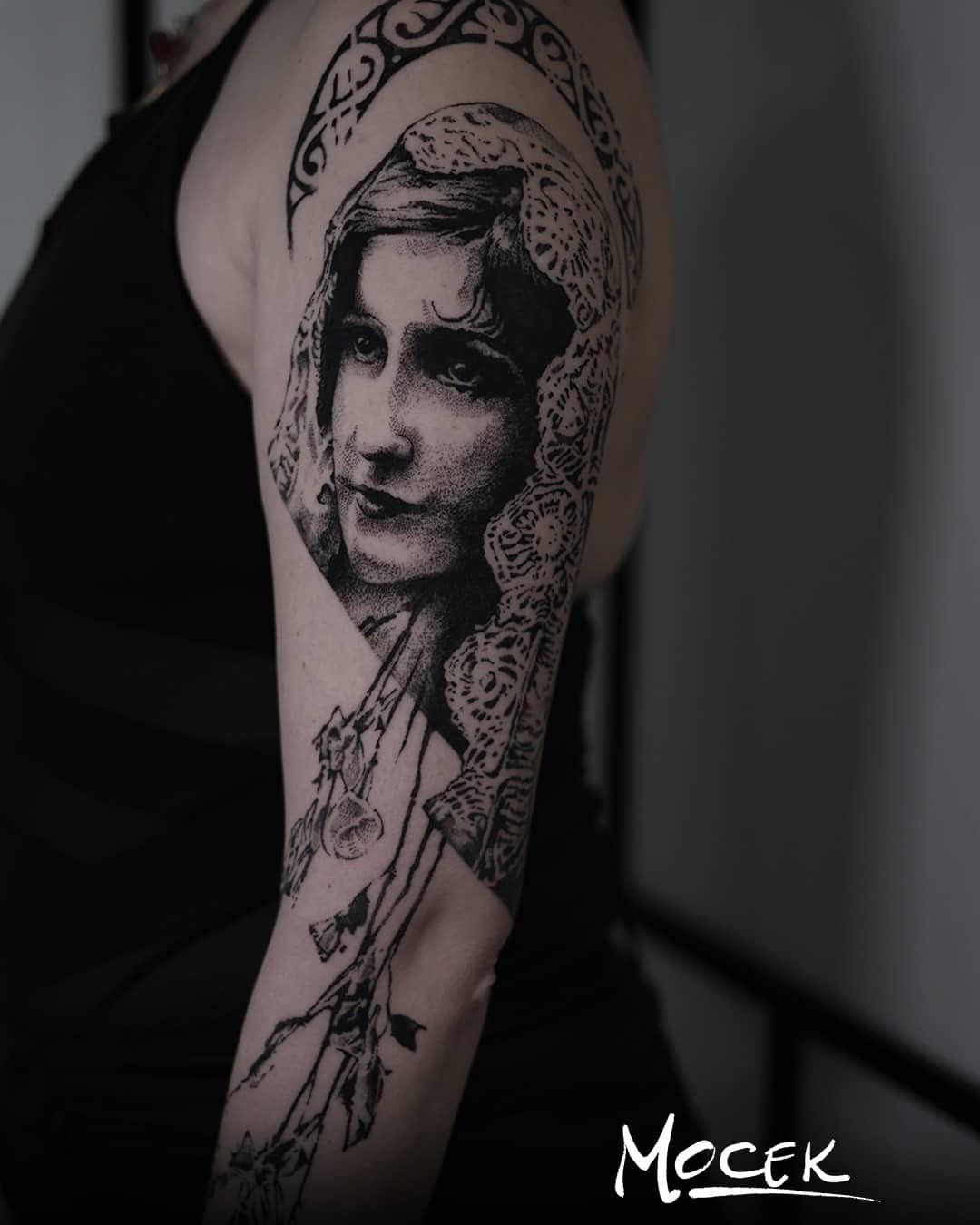 Tatuaż realistyczny kobiety z koronką i detalami florystycznymi, blackwork na ramieniu, wykonany przez Pawła Mocka, Sztorm Tattoo Gdańsk