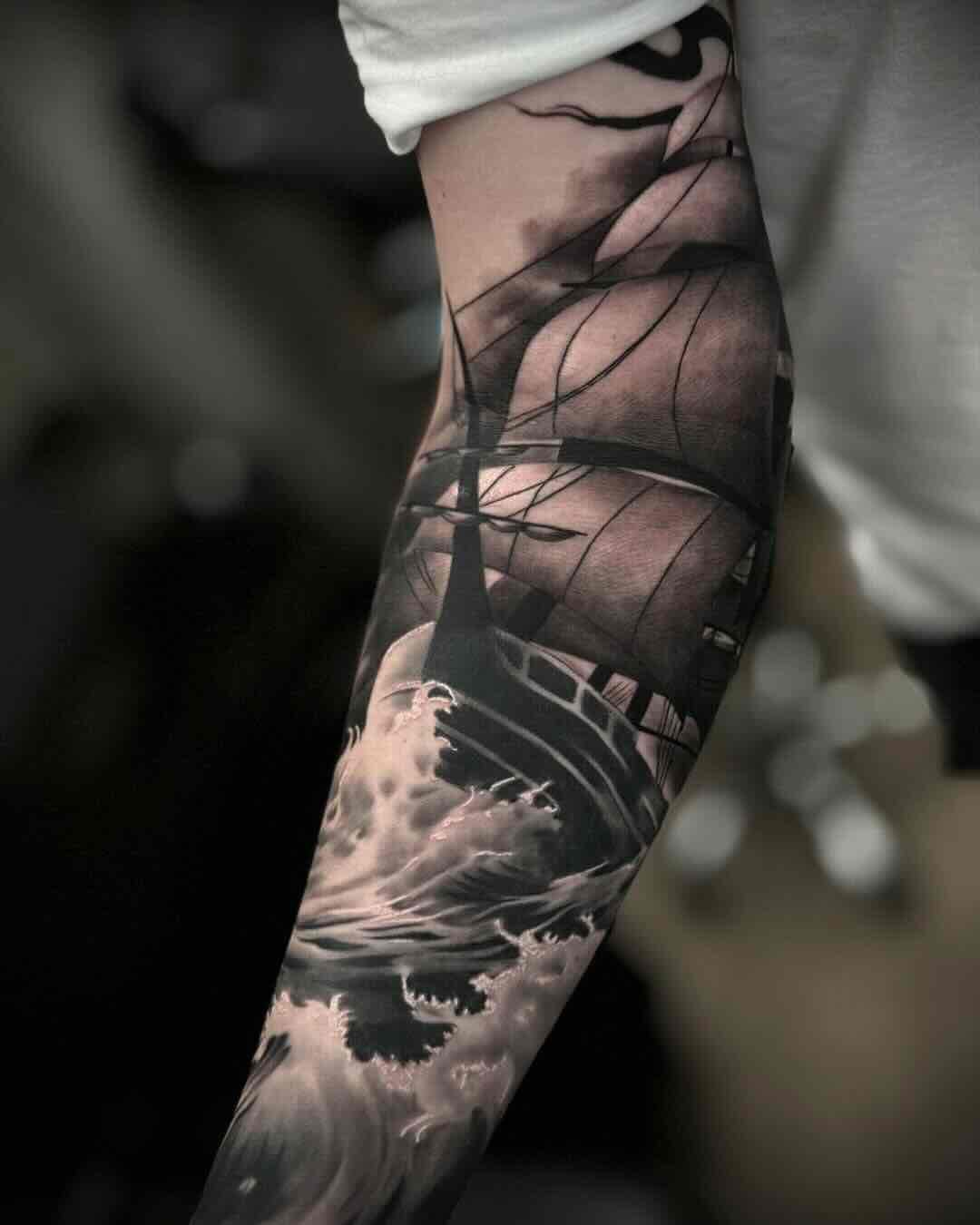 Tatuaż realistyczny przedstawiający żaglowiec na wzburzonym morzu, dynamiczny czarno-szary projekt wykonany przez Kolosa, Sztorm Tattoo Gdańsk.