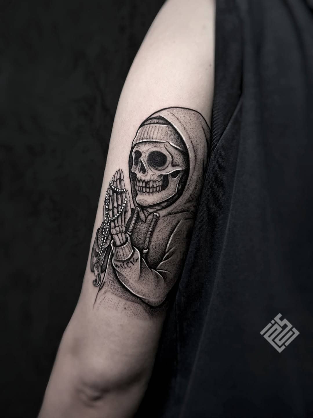 Tatuaż szkielet w bluzie z kapturem w pozie modlitwy, czarny styl, na ramieniu, Sillou, Sztorm Tattoo Gdańsk